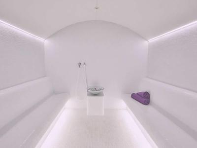 Jasny biały nowoczesny pokój sauny z długimi ławami i fioletowymi ręcznikami.