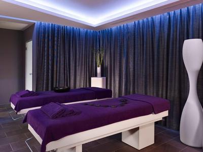 Nowoczesny pokój spa z dwoma stołami do masażu i klimatycznym oświetleniem.