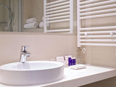 Modernes Hotelbadezimmer mit weißer Waschschale, Handtüchern und Pflegeprodukten.