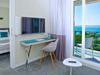 Moderner Hotelraum mit Schreibtisch, Stuhl und Balkon mit Meerblick.