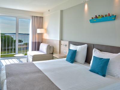 Modern eingerichtetes Hotelzimmer mit zwei Betten, Balkon und Meerblick.