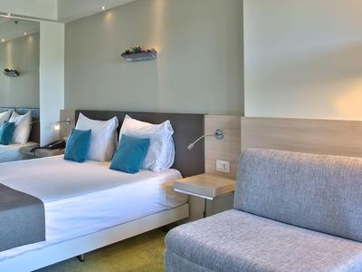 Modern eingerichtetes Hotelzimmer mit Doppelbett, Sitzbereich und ruhiger Farbgestaltung.