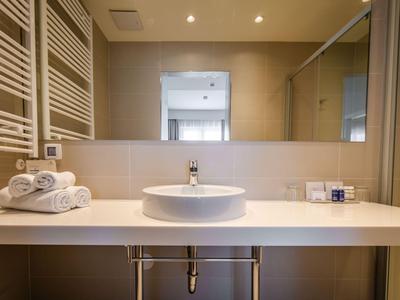 Modernes Badezimmer mit rundem Waschbecken, Spiegel und Handtüchern auf heller Oberfläche.