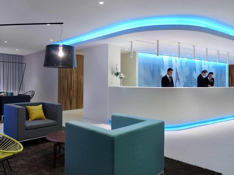 Nowoczesna lobby hotelowa z niebiesko podświetlonym recepcją i stylową strefą wypoczynkową.
