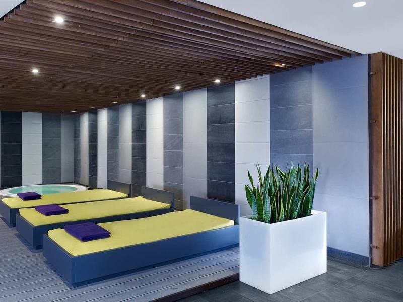 Nowoczesny pokój relaksacyjny z leżakami, białymi donicami i drewnianym sufitem w spa lub hotelu.