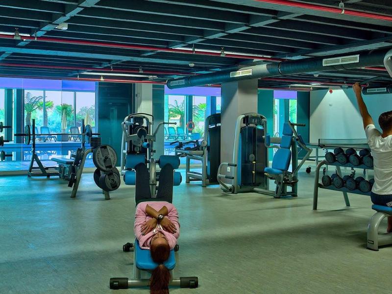 Nowoczesna siłownia z hantlami, maszynami i dwie osoby ćwiczące