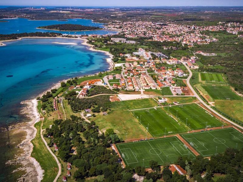 Widok z lotu ptaka na nadmorskie miasto z plażami, zielonymi polami i osiedlami mieszkalnymi.