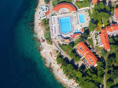 Widok z powietrza na hotel nad morzem z basenem i budynkami z czerwonymi dachami