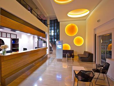 Nowoczesna lobby hotelowa z drewnianymi elementami i ciepłymi, okrągłymi światłami ściennymi.