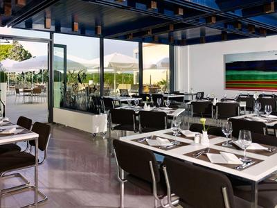 Nowoczesna restauracja z czarnymi krzesłami i dużymi oknami, które wpuszczają dużo światła dziennego.