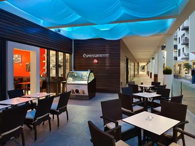 Nowoczesny zewnętrzny obszar restauracji z stołami i krzesłami pod niebieskim namiotem.