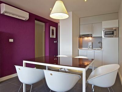 Nowoczesna kuchnia i jadalnia z fioletową ścianą, białymi meblami i wbudowanym mikrofalą.