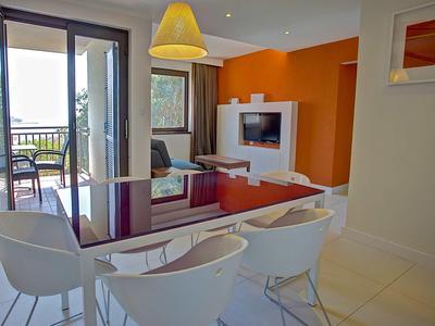 Nowoczesny salon z stołem jadalnym, białymi krzesłami i widokiem na balkon i morze.