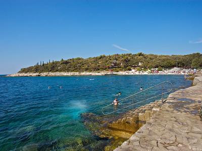 Czysta woda i skaliste wybrzeże z pływakami pod niebieskim niebem.