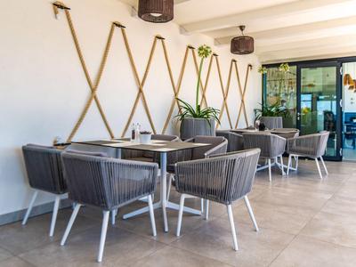 Nowoczesny zewnętrzny obszar hotelowy z szarymi krzesłami i stołami na szarej podłodze.