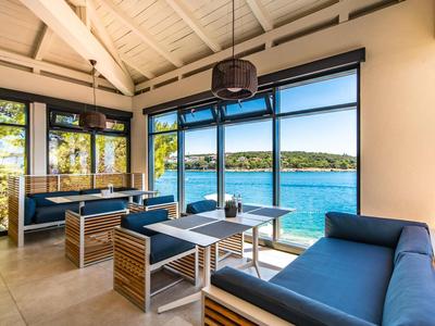Intérieur moderne avec canapé et grande fenêtre donnant sur un lac.