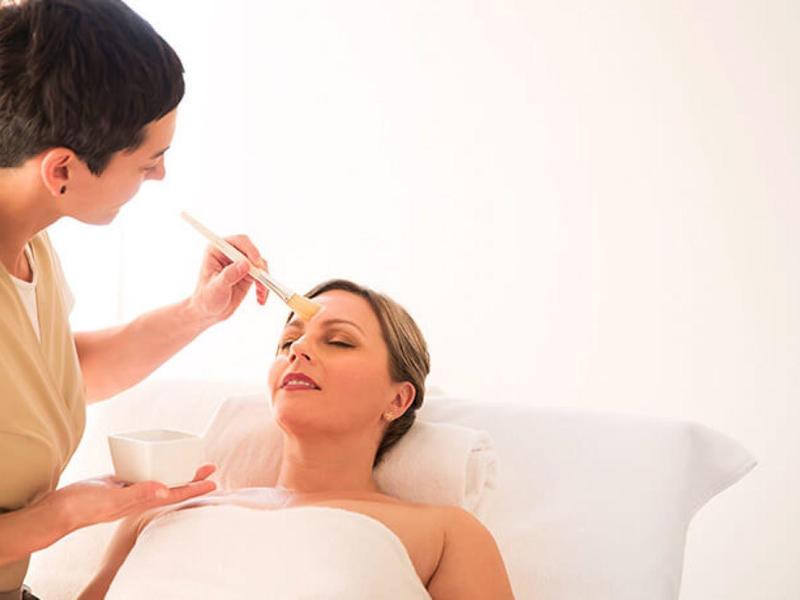 Žena dostává relaxační ošetření obličeje v jasné spa místnosti.