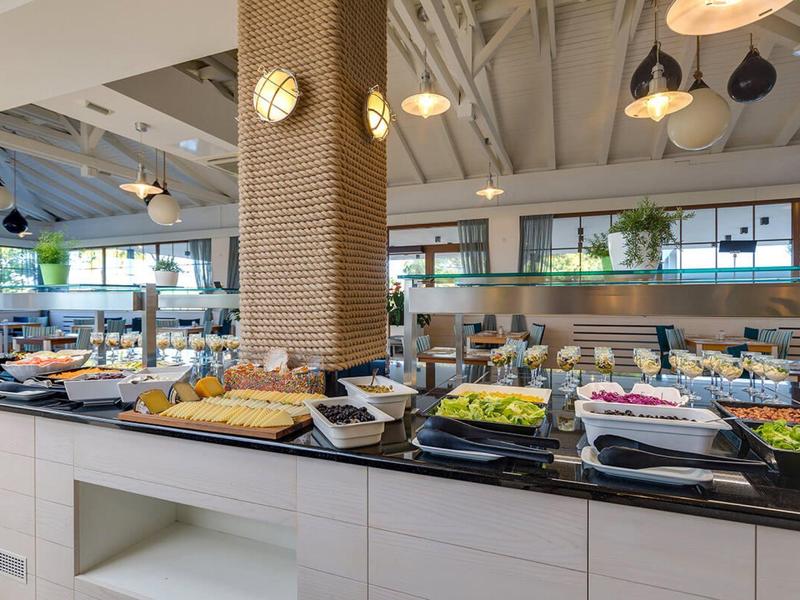 Jasně osvětlená snídaňová část s rozmanitým bufetem v moderním hotelu.