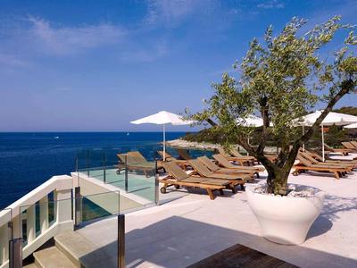 Luxusní hotelová terasa s lehátky s výhledem na modré moře pod jasnou oblohou.