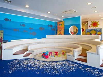 Heller, bunter Kinderspielraum mit runden weißen Sitzstufen und maritimen Wandbildern.