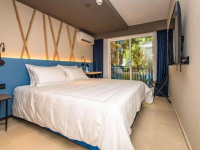 Modernes Schlafzimmer mit großem Bett, blauer Wand, Holzdekor und Balkon mit Gartenblick.