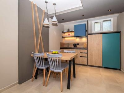 Moderner Küchenbereich mit Holzmöbeln, blauen Akzenten, Essbereich und Pendelleuchten.