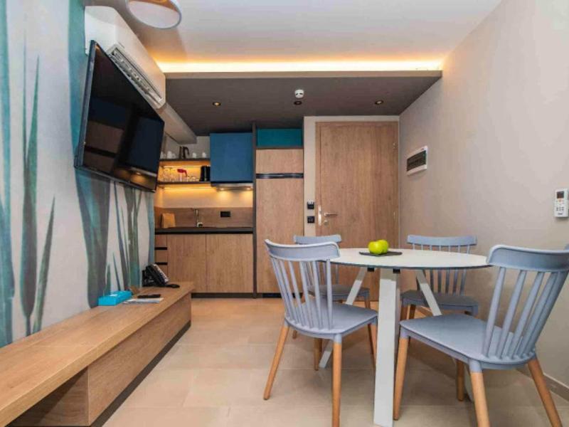 Moderner Küchen- und Essbereich mit runden Tisch, blauen Stühlen, Holzmöbeln und Fernseher an der Wand.