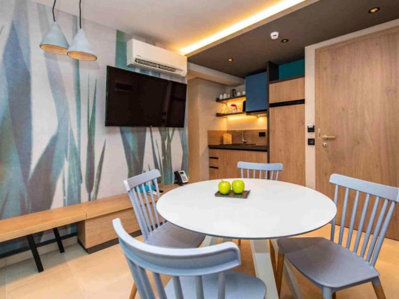 Moderner Essbereich mit runder weißer Tischplatte, vier grauen Stühlen und Küchenzeile im Hintergrund.