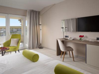 Moderní hotelový pokoj s postelí, stolem, židlí a balkonem s výhledem.