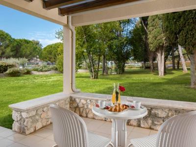 Pohodlná terasa se stolem a židlemi na zahradě s stromy a trávníkem