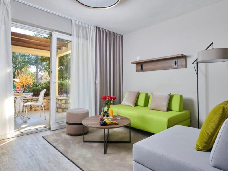Pohodlný obývací pokoj se zelenou pohovkou, konferenčním stolkem a přístupem na terasu.