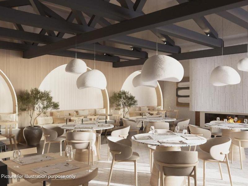 Moderní světlá restaurace s kulatými stoly, židlemi a velkými bílými závěsnými lampami.