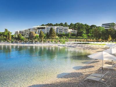 Playa con tumbonas y sombrillas frente a un hotel moderno junto al mar