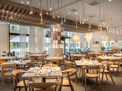 Restaurante moderno y luminoso con sillas de madera y grandes ventanas, listo para invitados.