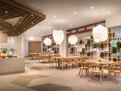 Moderner, heller Speisesaal mit Holz- und Metalldekor, runden Lampen und Pflanzenregal an der Wand.