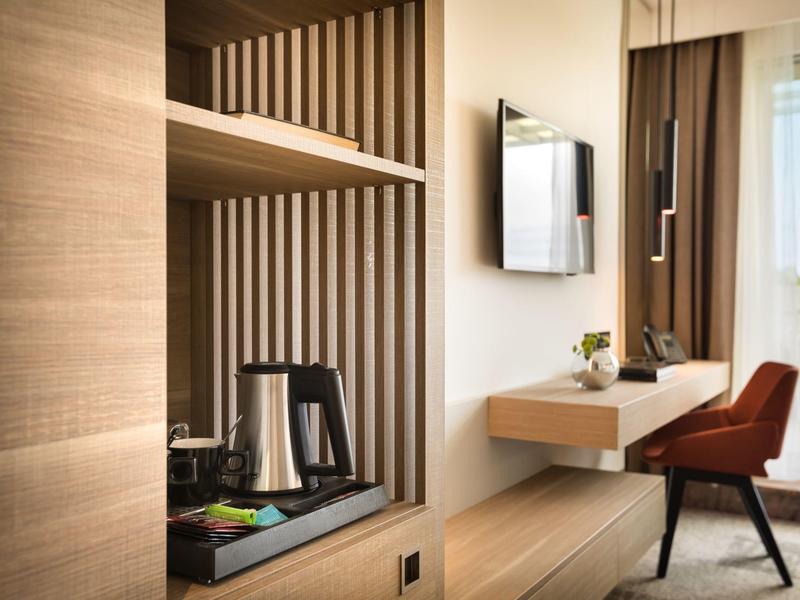 Moderner Arbeitsbereich mit Holzregalen, rotbraunem Stuhl, kleinem Schreibtisch und TV an der Wand.