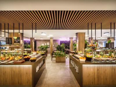 Prostorná bufetová oblast s vystavenými jídly, dřevěnými akcenty a moderním osvětlením.