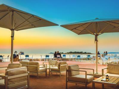 Terras met stoelen en parasols bij zonsondergang met uitzicht op de zee.