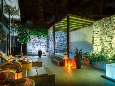 Pohodlná venkovní terasa s kamennými zdmi, komfortním posezením a ambientním osvětlením v noci.