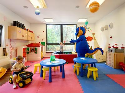 Ein bunter Spielraum mit Kinderspielzeug und einer Person in einem blauen Drachenkostüm.
