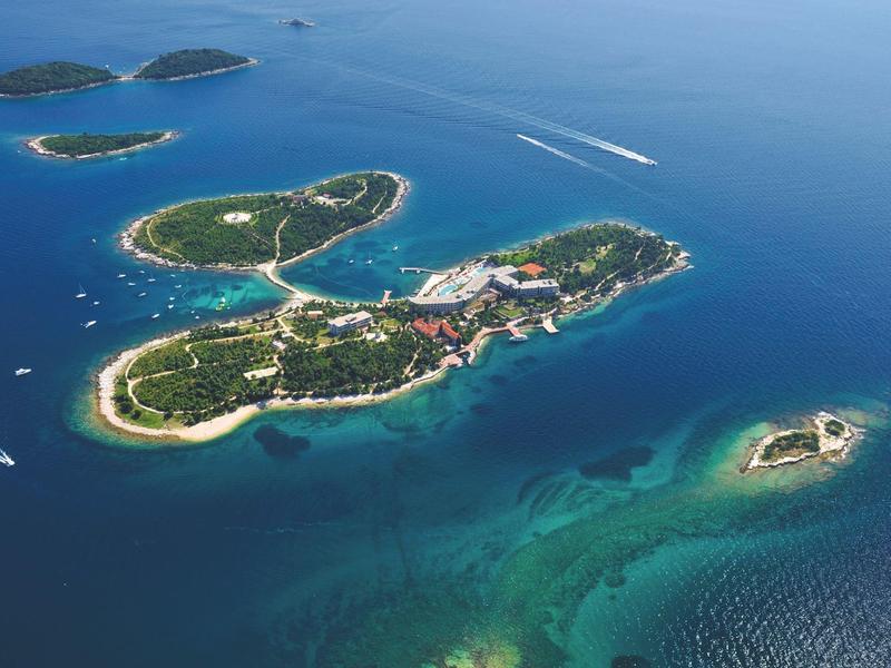 Letecký pohled na malé tropické ostrovy se zelenou vegetací obklopené modrou oceánskou vodou.