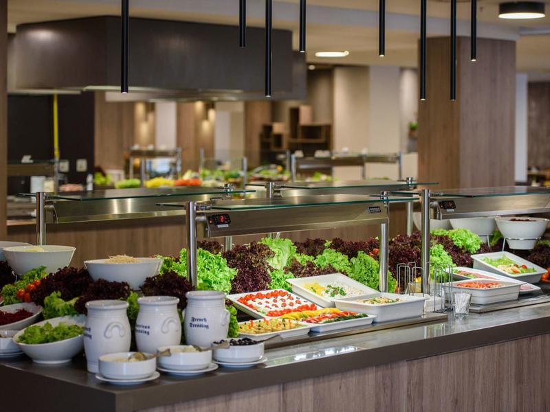 Čerstvý salátový bar s různou zeleninou a dresinky v moderní jídelně.
