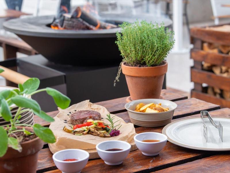 Tisch mit Pflanzen, Wrap, Schalen mit Soßen und Getränk in Holzhalle, helle Tagesbeleuchtung.