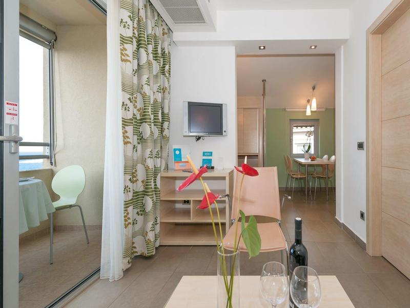 Moderner, heller Wohnraum mit Glasschiebetür, Holzschrank, Tisch, Stühlen und Pflanze im Vordergrund.