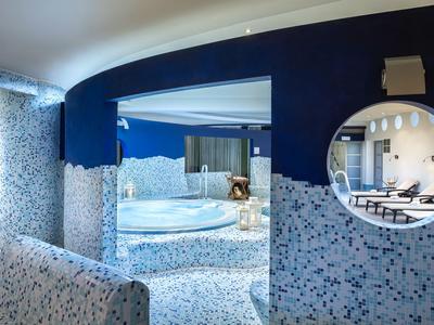 Moderner Wellnessbereich mit Mosaikfliesen, Whirlpool und Sitzgelegenheiten unter blauen Wänden.