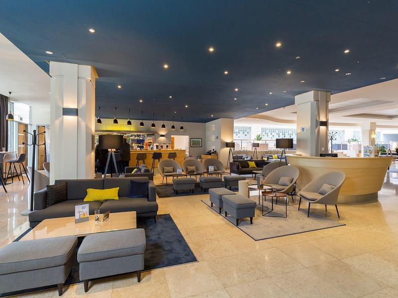 Hall d'hôtel moderne avec canapés confortables, fauteuils et sol en marbre clair.