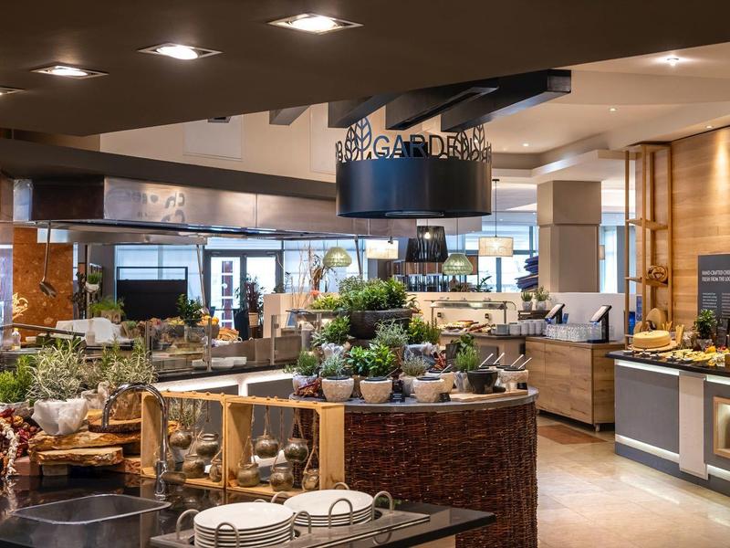 Bar d'hôtel moderne avec éclairage élégant et variété de plantes et décorations.