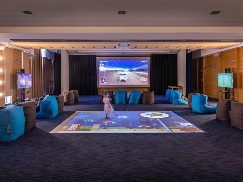 Salle d'attente moderne avec fauteuils bleus et grands écrans dans un hôtel.