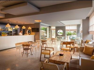 Lichte hotelkamer met moderne meubels, tafels, stoelen en panoramische ramen.