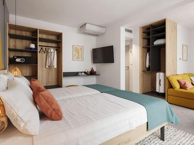 Moderne hotelkamer met bed, open kledingkast en comfortabele stoel.